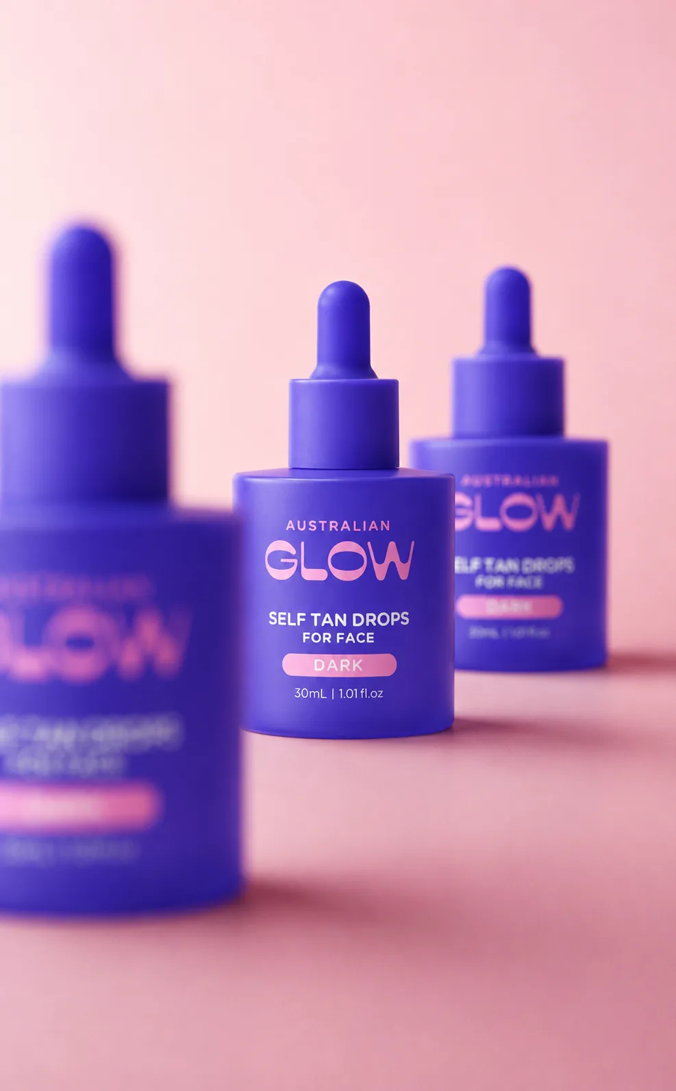 Face Tan Drops trio on a pink backdrop